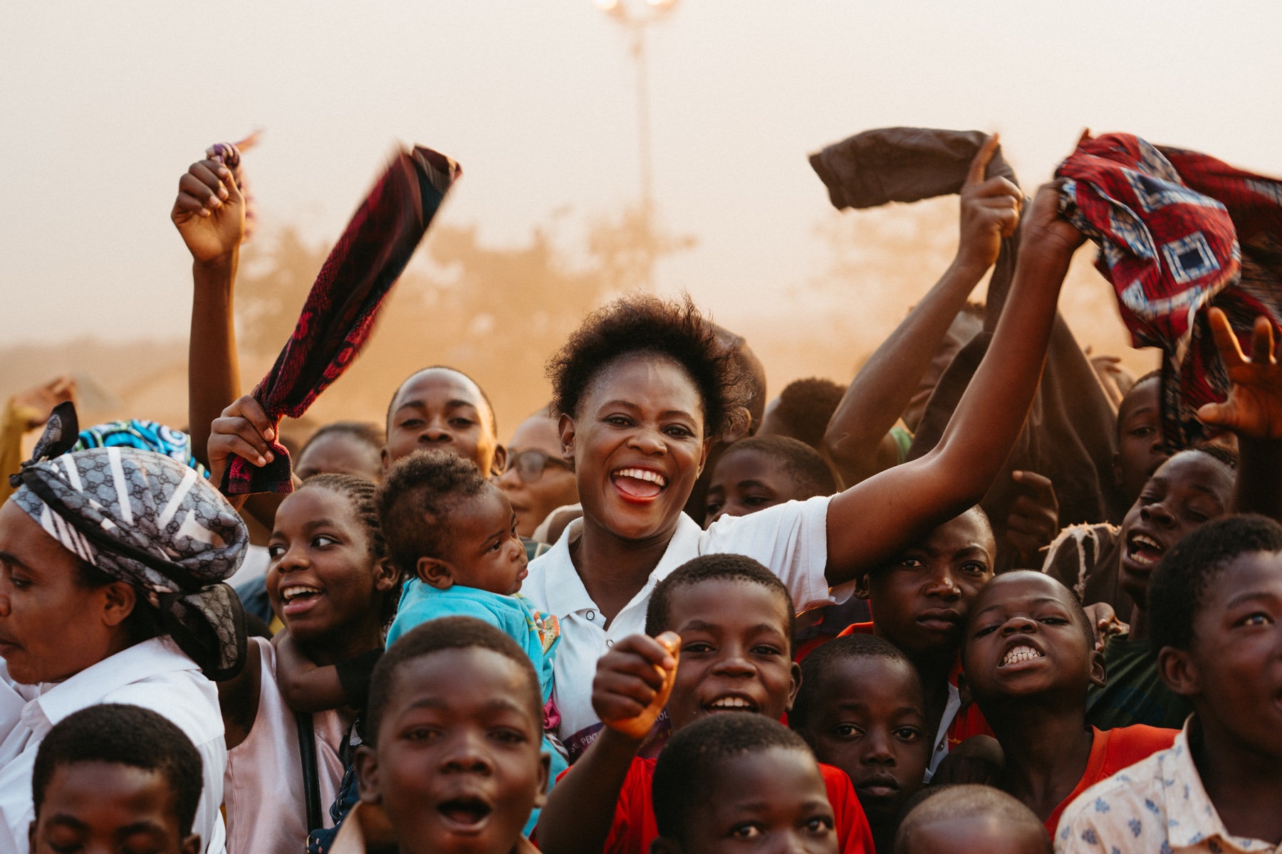 A joyful crowd of adults and children with raised hands